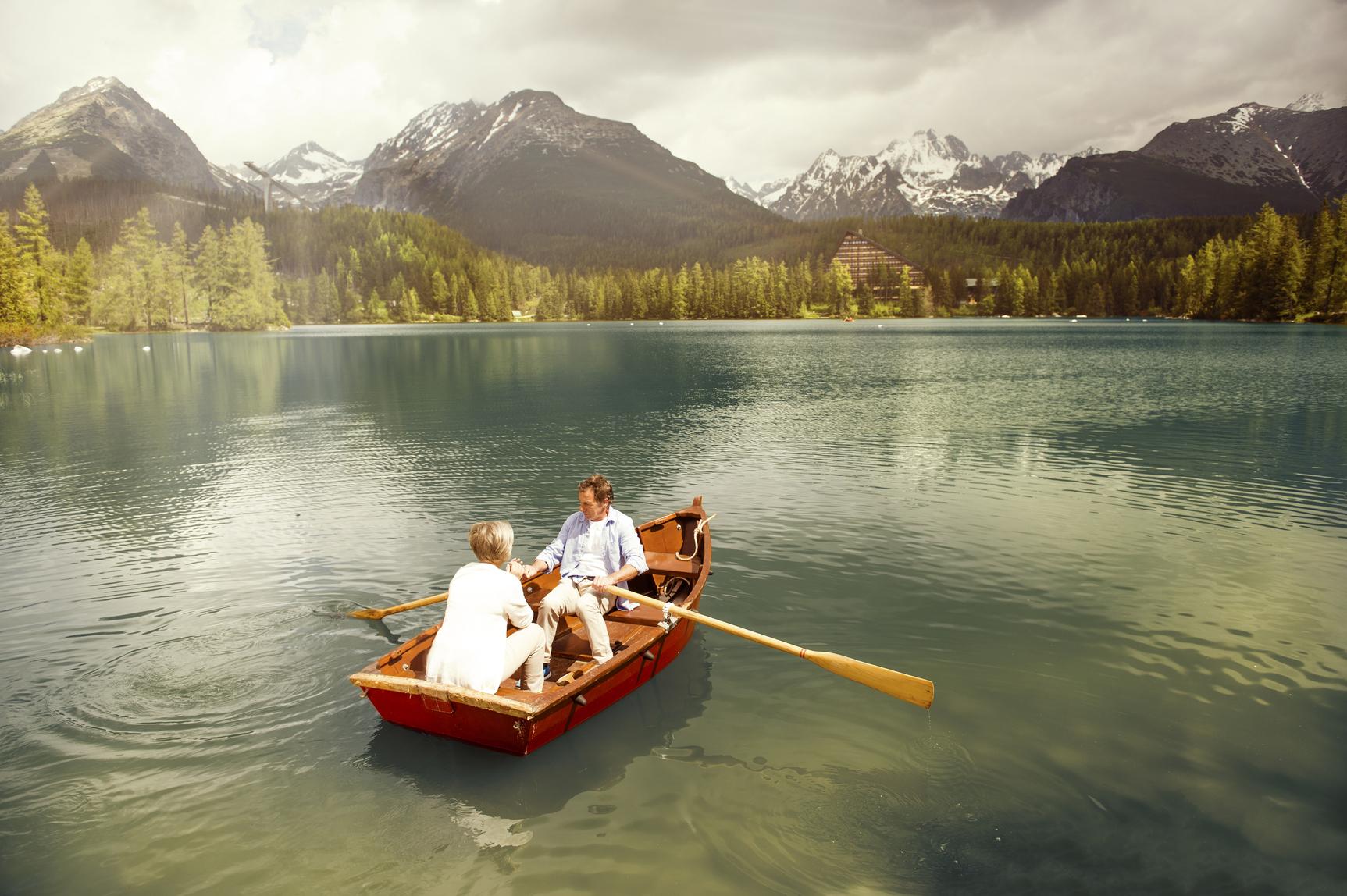Couple paddling on boat with mountains in the distance